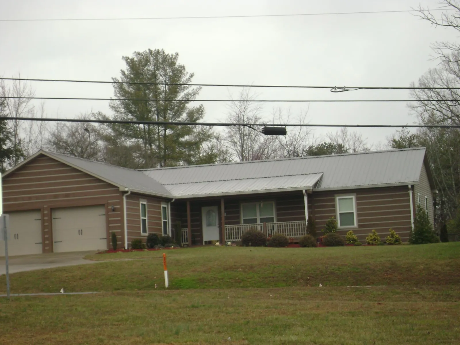 Gray metal roof on a log sided ranch home with a front porch in Batavia